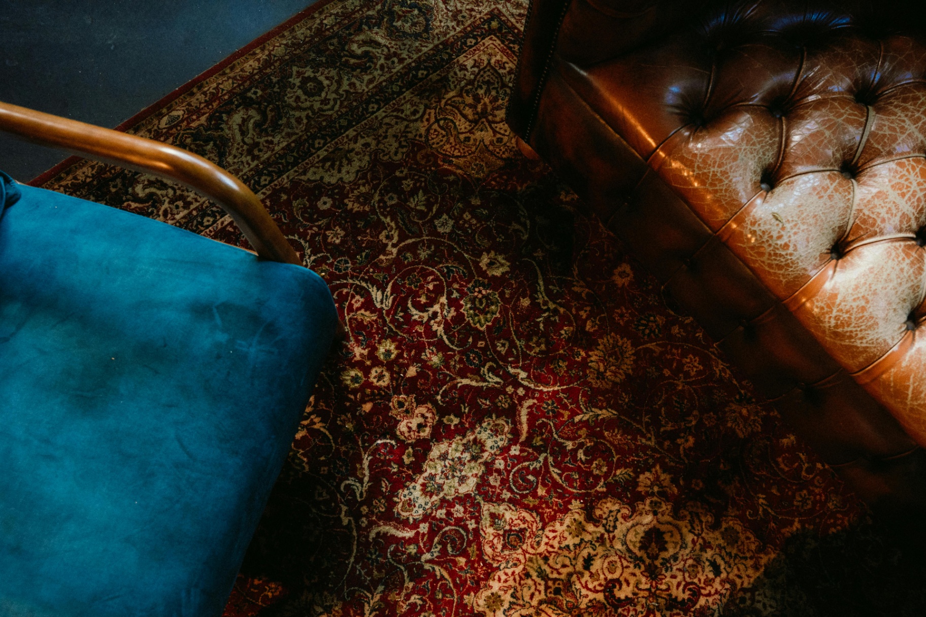 Sala interior elegante con tapete persa Safron Rugs colgado en pared sobre sofá verde salvia